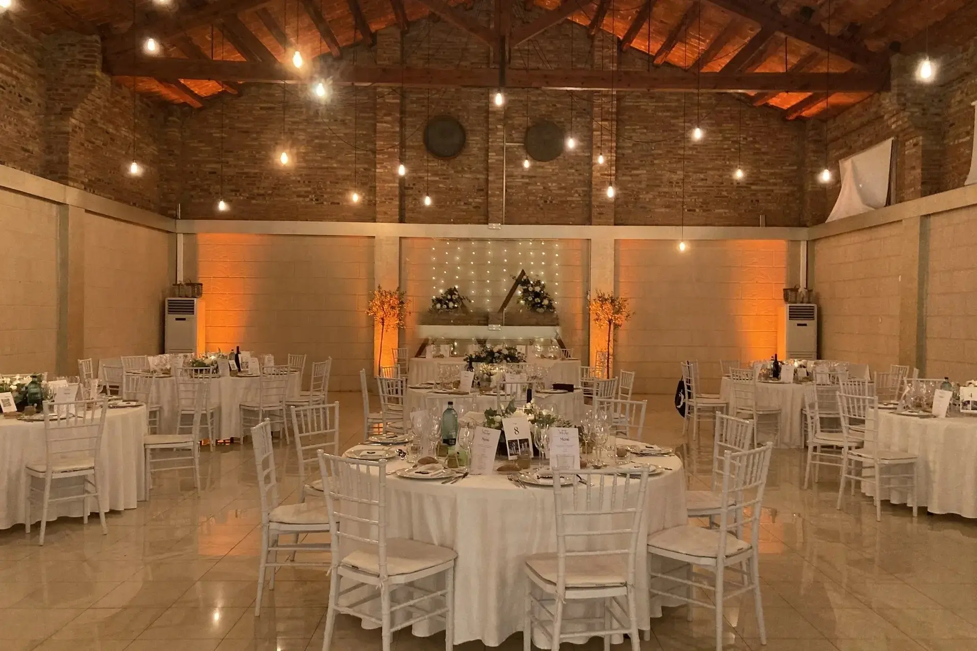 La mesa presidencial con un fondo de luces, flores en forma de triángulo y árboles pequeños iluminados a cada lado